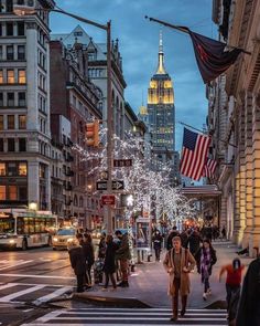 people are walking down the street in front of buildings with christmas lights and american flags