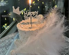 a birthday cake with white feathers and a candle