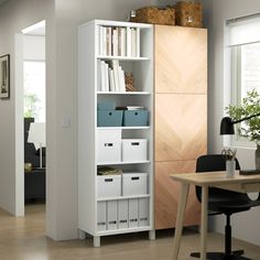 a white bookcase filled with lots of books next to a wooden table and chair