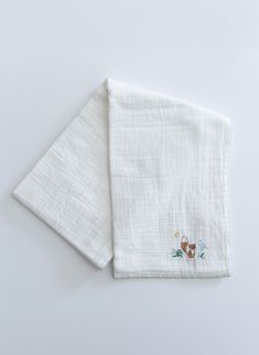 two white napkins with embroidered animals on them