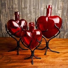 three red heart shaped vases sitting on top of a wooden table