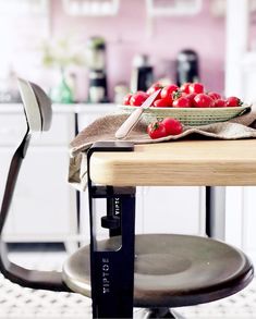 a bowl of tomatoes sitting on top of a wooden table