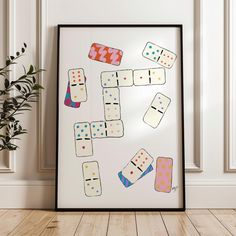 a frame with some dominos on it next to a potted plant in a room