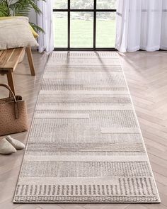 a white rug with lines on the floor in front of a window and a wooden bench