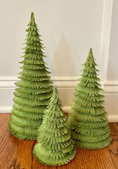 three small green trees sitting on top of a wooden floor