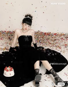 a woman in a black dress sitting on the floor with confetti all around her