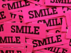 pink and black stickers with the words smile written on them are piled up together