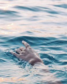 a person swimming in the ocean with their hand out to touch the water's surface