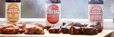 three bottles of meat sitting on top of a wooden cutting board next to some ribs