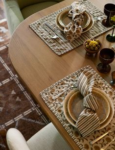 a wooden table topped with plates and place settings