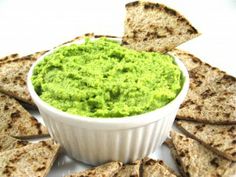 a white bowl filled with guacamole surrounded by tortilla chips