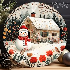 a christmas card with a snowman in front of a snowy house and pine cones