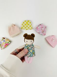 a hand holding a small doll surrounded by baby hats