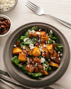 a salad with nuts and feta cheese in a bowl next to two bowls on a table