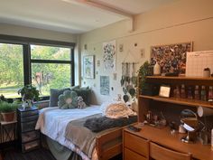 a bed room with a neatly made bed and lots of plants in the window sill