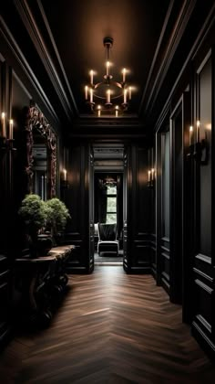 an elegant hallway with black walls and wood flooring, chandelier and mirror