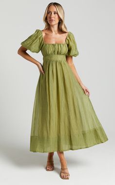 a woman in a green dress posing for the camera with her hands on her hips