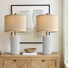 two lamps sitting on top of a wooden dresser