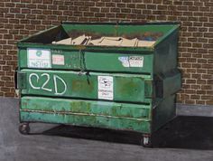 a large green box sitting on the side of a road next to a brick wall