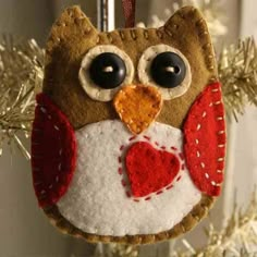 an owl ornament hanging from a christmas tree with red and white felt on it