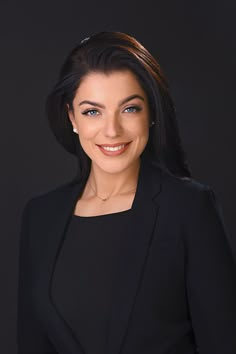 a woman in a black suit smiling at the camera