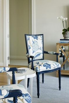 a blue and white chair sitting in a living room next to a vase with flowers on it