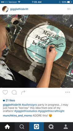 a woman is painting on a wooden sign