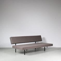 a gray couch sitting on top of a white floor in front of a grey wall