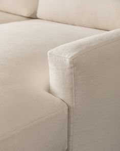 a close up view of the back end of a couch with white linen on it