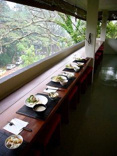 a long table with plates of food sitting on it in front of a large window