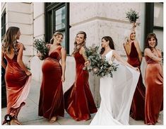 a group of women standing next to each other wearing dresses and holding bouquets in their hands