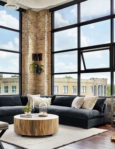 a living room filled with furniture next to large windows and a tall brick building in the background