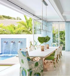 a dining room table with green chairs next to a pool and water feature in the background