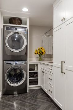 a washer and dryer are in the corner of this laundry room with white cabinets