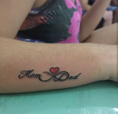 a woman with a tattoo on her arm that says mom and dad