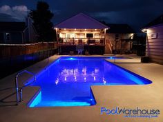 a swimming pool lit up at night with blue lights on the side and steps leading to it