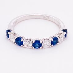 a blue and white diamond ring with five stones on the side, set in 18k white gold