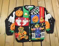 an ugly sweater with pumpkins and ghostes on it sitting on a wooden floor