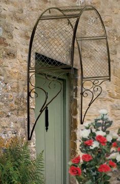 a green door with an iron frame and flower pot in front of it on the side of a stone building