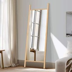 a wooden floor mirror sitting on top of a hard wood floor next to a bed