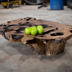 two green apples sitting on top of a piece of drift wood with holes in it