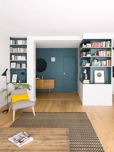 a living room filled with furniture and bookshelves next to a wooden floor covered in rugs