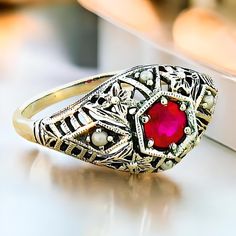 Discover a stunning piece of elegance with our Vintage Natural Ruby and Freshwater Pearl Accent Filigree Ring, meticulously crafted to elevate your jewelry collection. This exquisite ring features a vibrant, deep red natural ruby, surrounded by dainty freshwater pearls that gently complement its allure. Each ring is expertly crafted in quality 925 solid sterling silver, ensuring a timeless piece that shines with sophistication. The intricate filigree design showcases the artistry and attention to detail that defines exceptional vintage jewelry, making it a perfect choice for both everyday wear and special occasions. Whether you're dressing up for a night out or adding a touch of glamour to a casual outfit, this unique ring will surely draw admiration. To maintain its brilliant shine and be Elegant Cluster Ring With Birthstone For Anniversary, Vintage Pearl Ring With Gemstone, Formal Sterling Silver Birthstone Ring With Accent Stones, Classic Sterling Silver Birthstone Ring With Gemstone, Elegant Sterling Silver Ruby Ring Gift, Elegant Formal Cluster Ring With Birthstone, Exquisite Silver Ruby Ring, Exquisite Silver Round Ruby Ring, Formal Sterling Silver Birthstone Engraved Ring