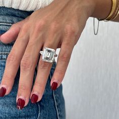 a woman's hand with a ring on her finger and red nail polish holding an engagement ring