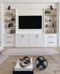 a living room with white cabinets and a flat screen tv mounted on the wall above it