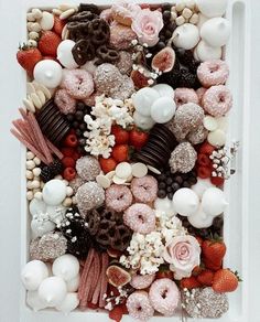 a white box filled with lots of different types of donuts and strawberries on top of each other