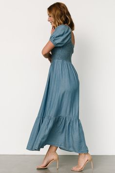 Versatile for any occasion Chambray blue color Soft material with no stretch Horseshoe neckline with elastic shoulders Smocked bodice Short sleeves with elastic cuffs Single tiered maxi skirt Unlined 100% Lyocell Marianne is 5'6, cup size 34D, size 6 and wearing size S