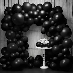 black and white photograph of balloons in the shape of an o - letter on a cake stand