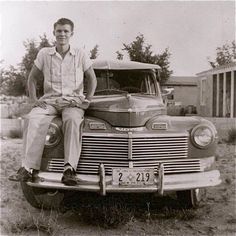 a man sitting on the hood of an old car