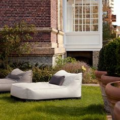 a white couch sitting on top of a green grass covered field next to a tall brick building